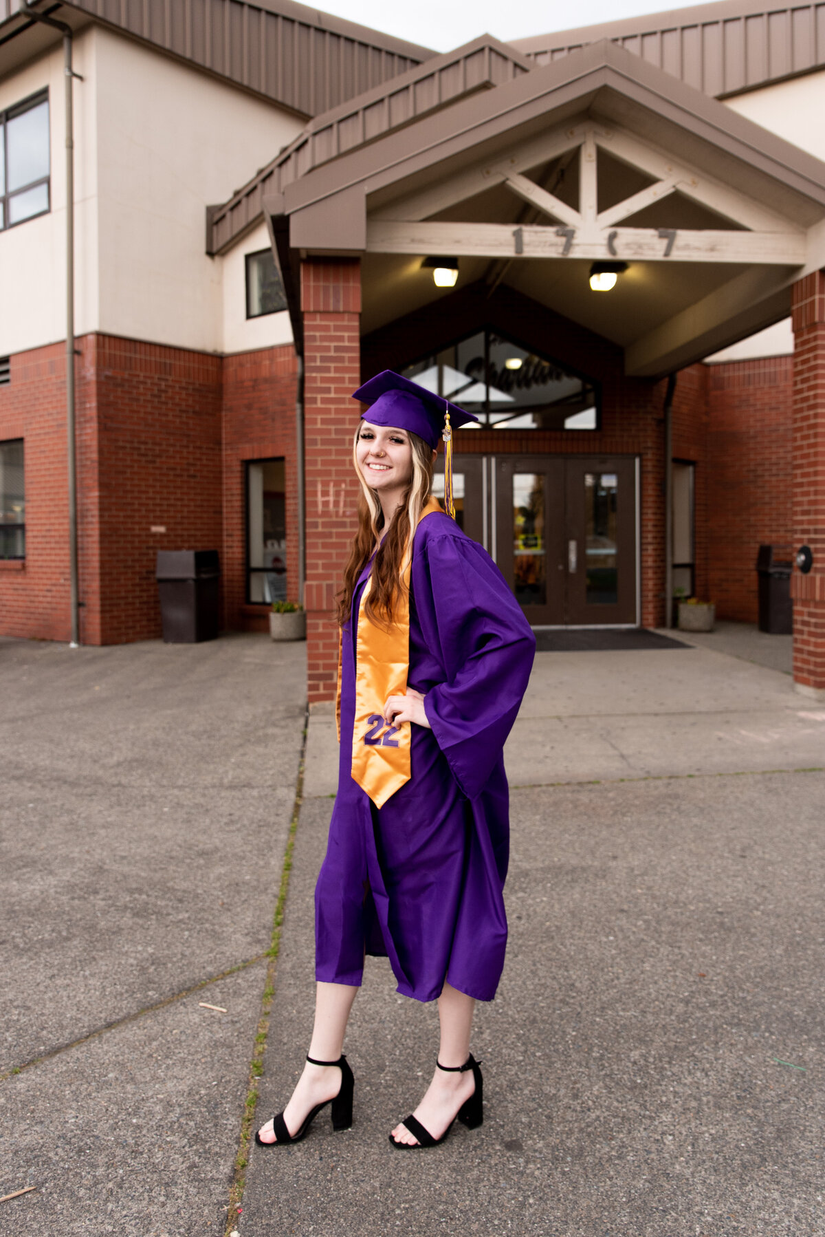 High school senior posed in front of Sumner High School for senior portraits wearing her cap and gown