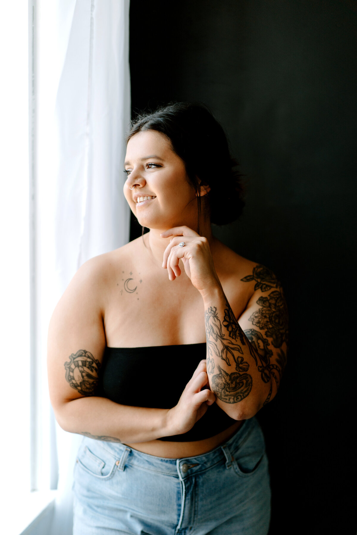 Girl facing towards window with tattoos on arm