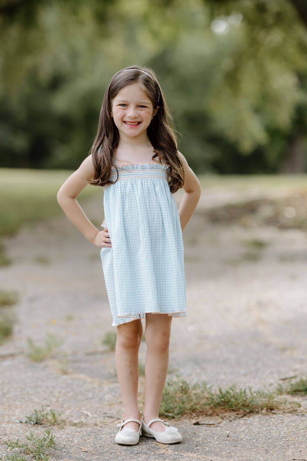 little girl in light blue dress smiling in open East Texas field