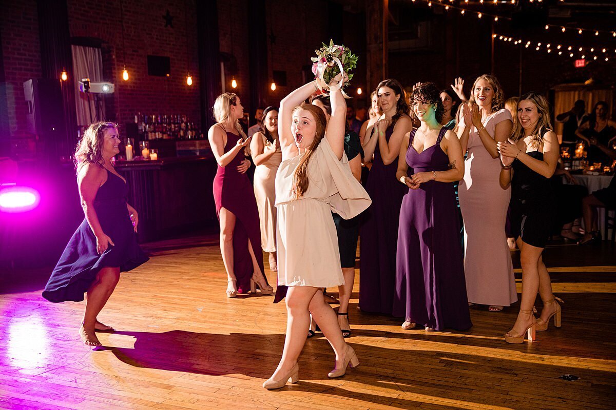 Guest jumping to catch bridal bouquet