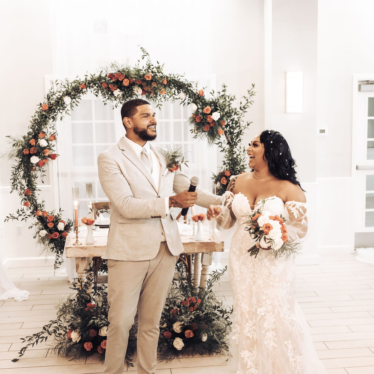 bride and groom standing in front of reception table that is decorated with orange and white roses