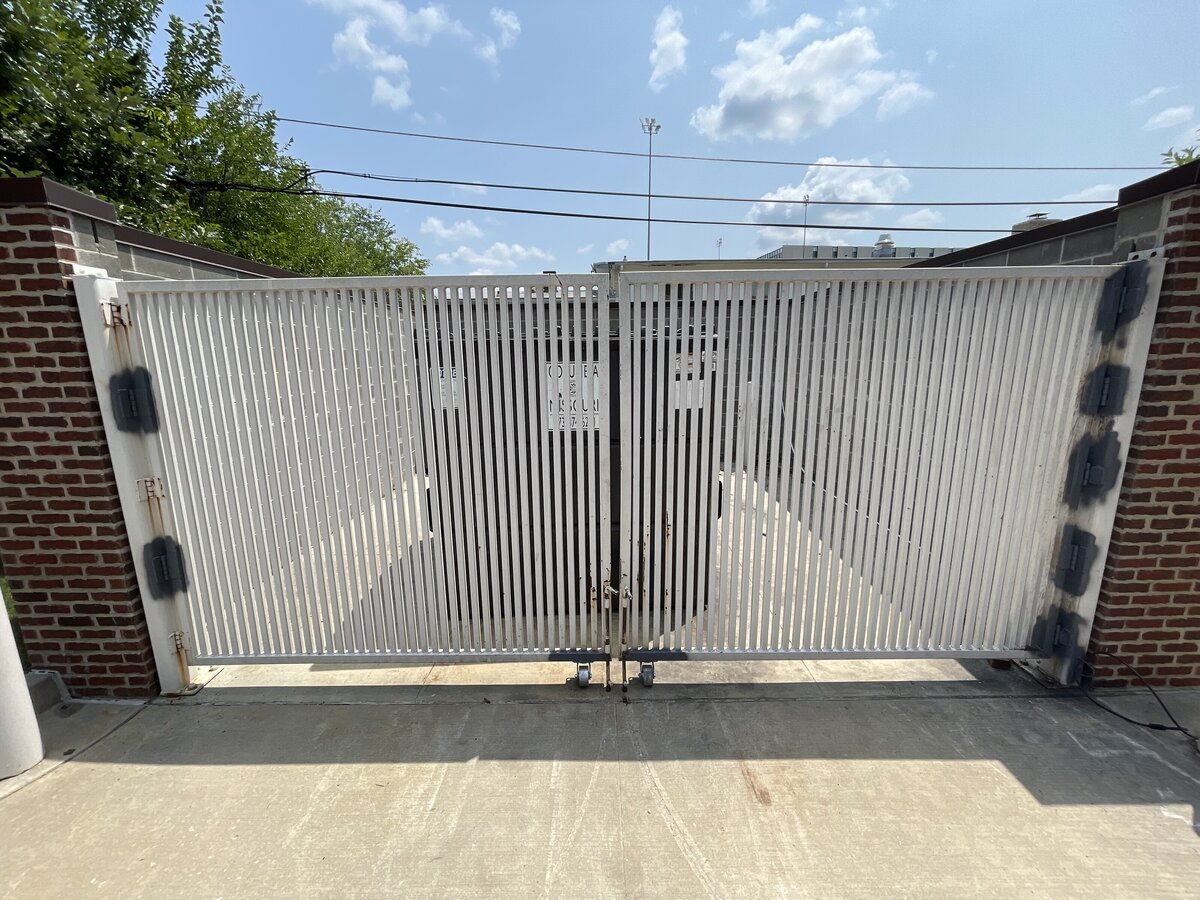 Welded steel trash enclosure gate installed at a commercial property to secure and conceal waste disposal areas.