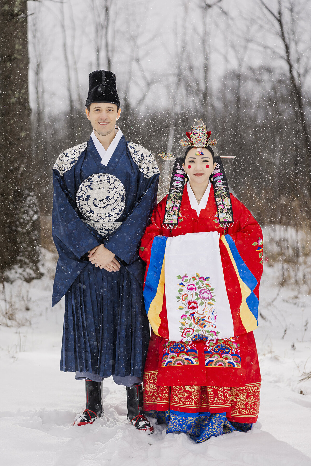 Winter wedding portrait of a couple in traditional Korean hanbok in the falling snow