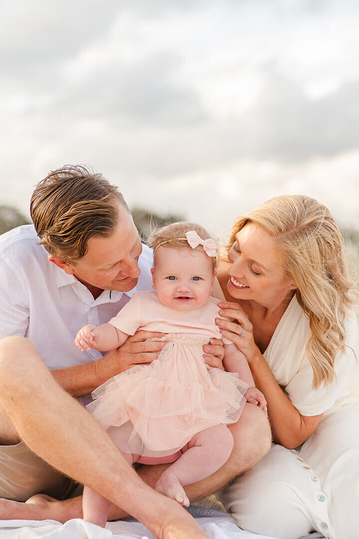 candid beach memories: Mum and dad holding baby, captured by brisbane family photographer Hikari