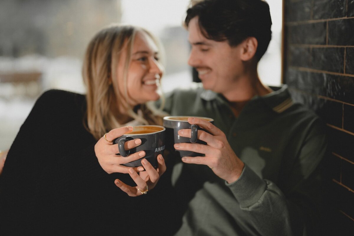 Engaged couple looking at each other and holding coffee cups at Analog Coffee in Calgary