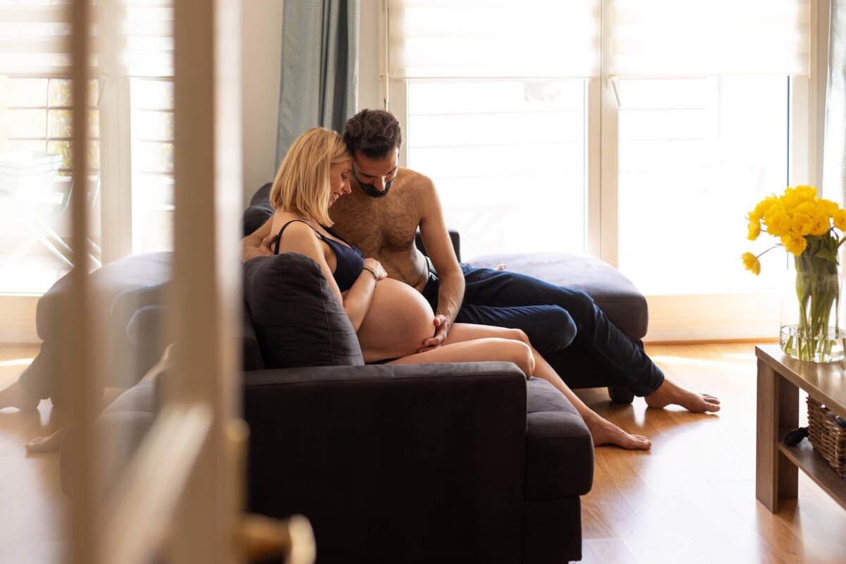 photo à domicile lumineuse homme regardant et caressant le ventre de sa femme enceinte