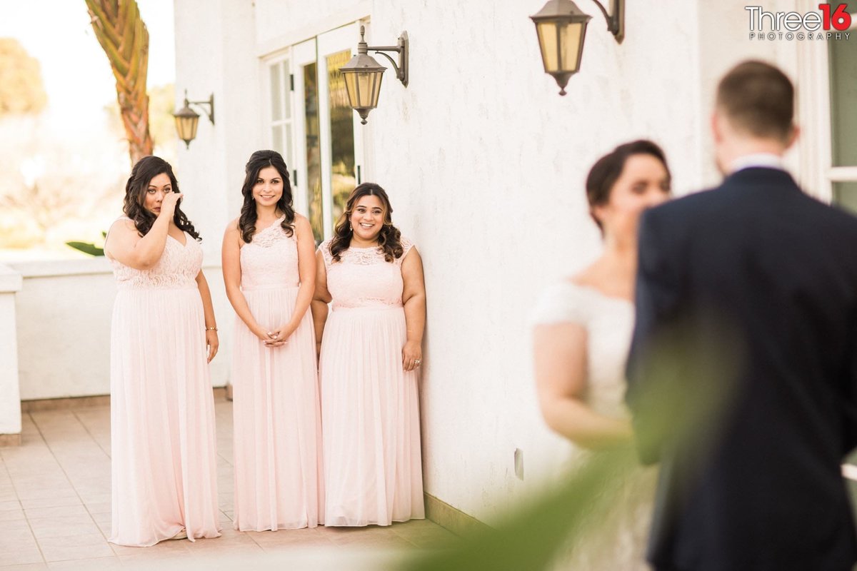 Bridesmaids watch as the Bride and Groom pose for photos