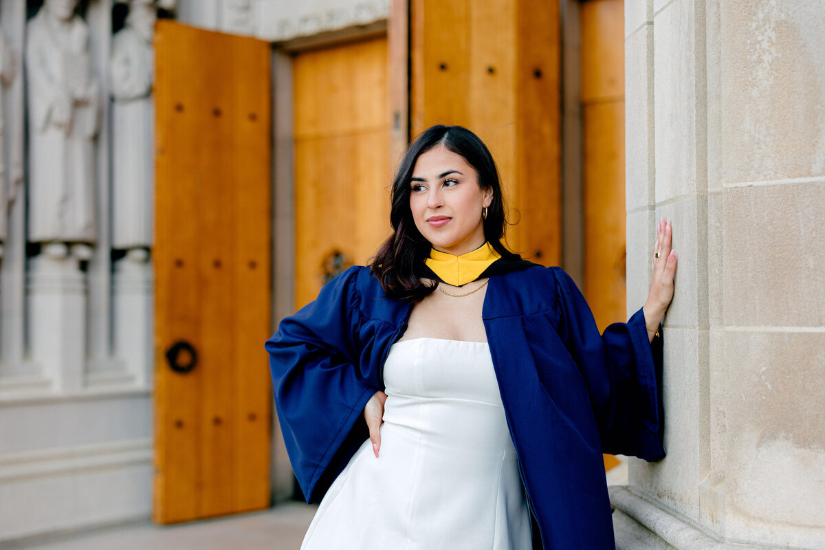 Duke University graduate in gown and hood leaning against the wall at Duke Chapel.