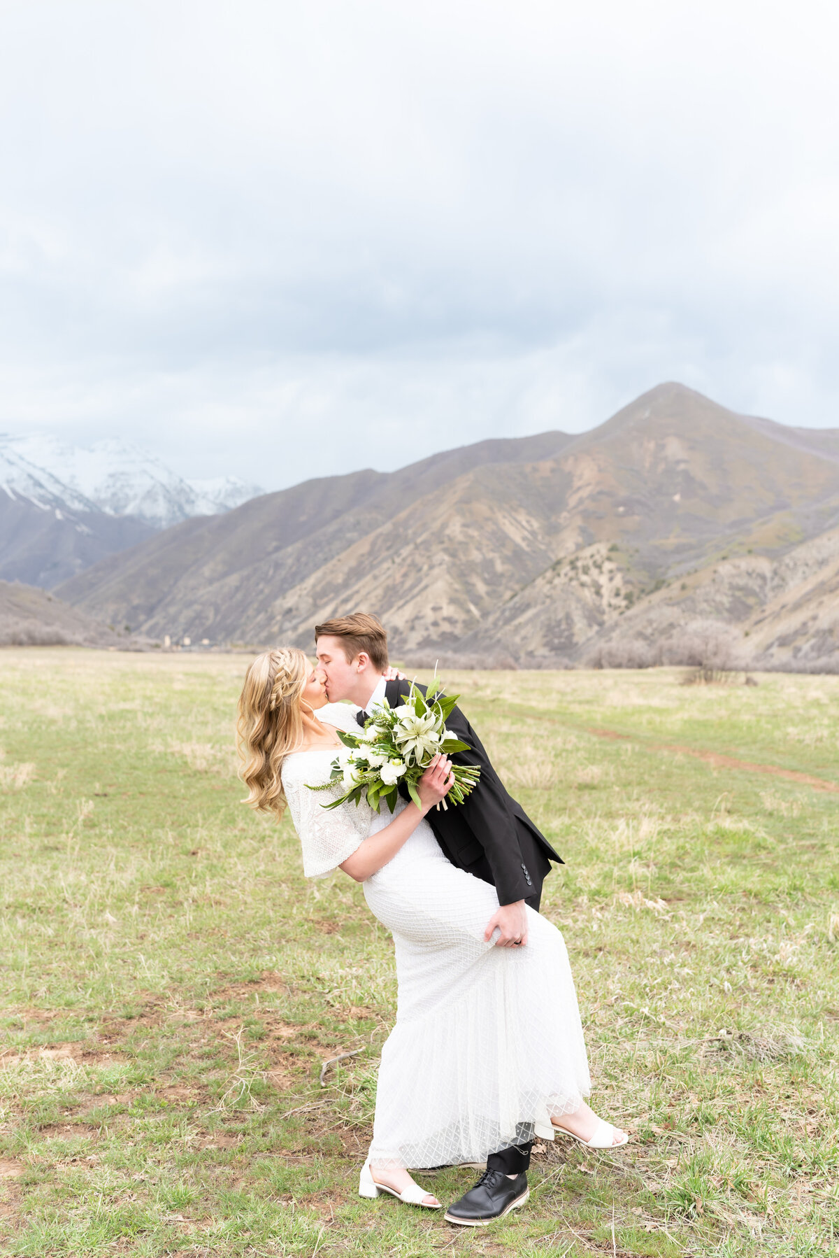 Groom kissing his bride with mountain landscape