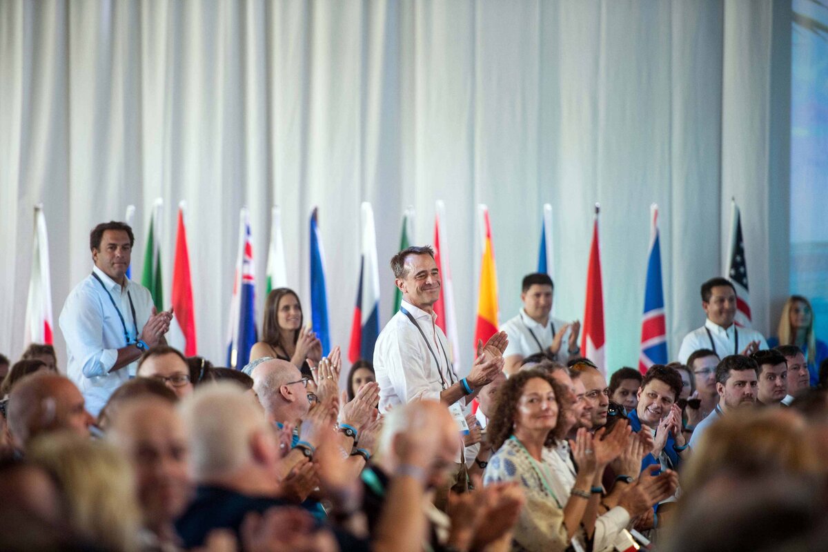 A crowd of top sales people clap at an international destination event