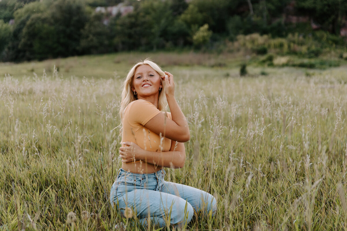 A girl crouched down in a field with tall grass