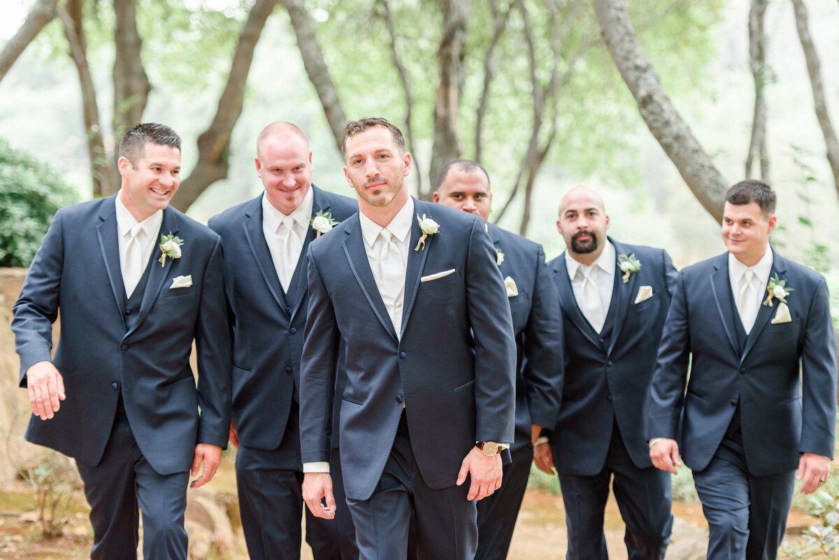 groom walking in the woods with ushers