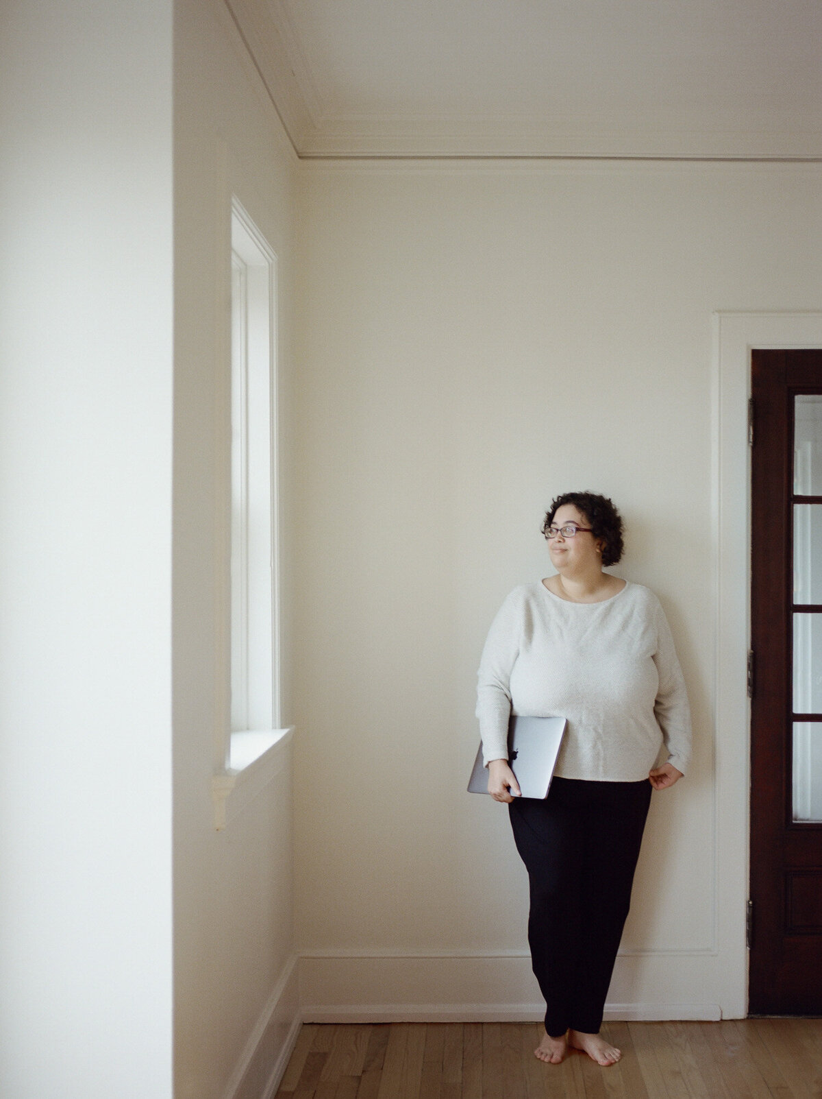 woman with curly dark hair, white sweater, folded macbook, web designer brand photography in Michigan