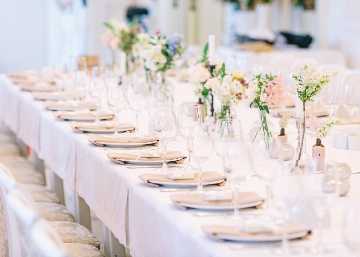 A white and peach table set up for a wedding or a luxury event with spring flowers.