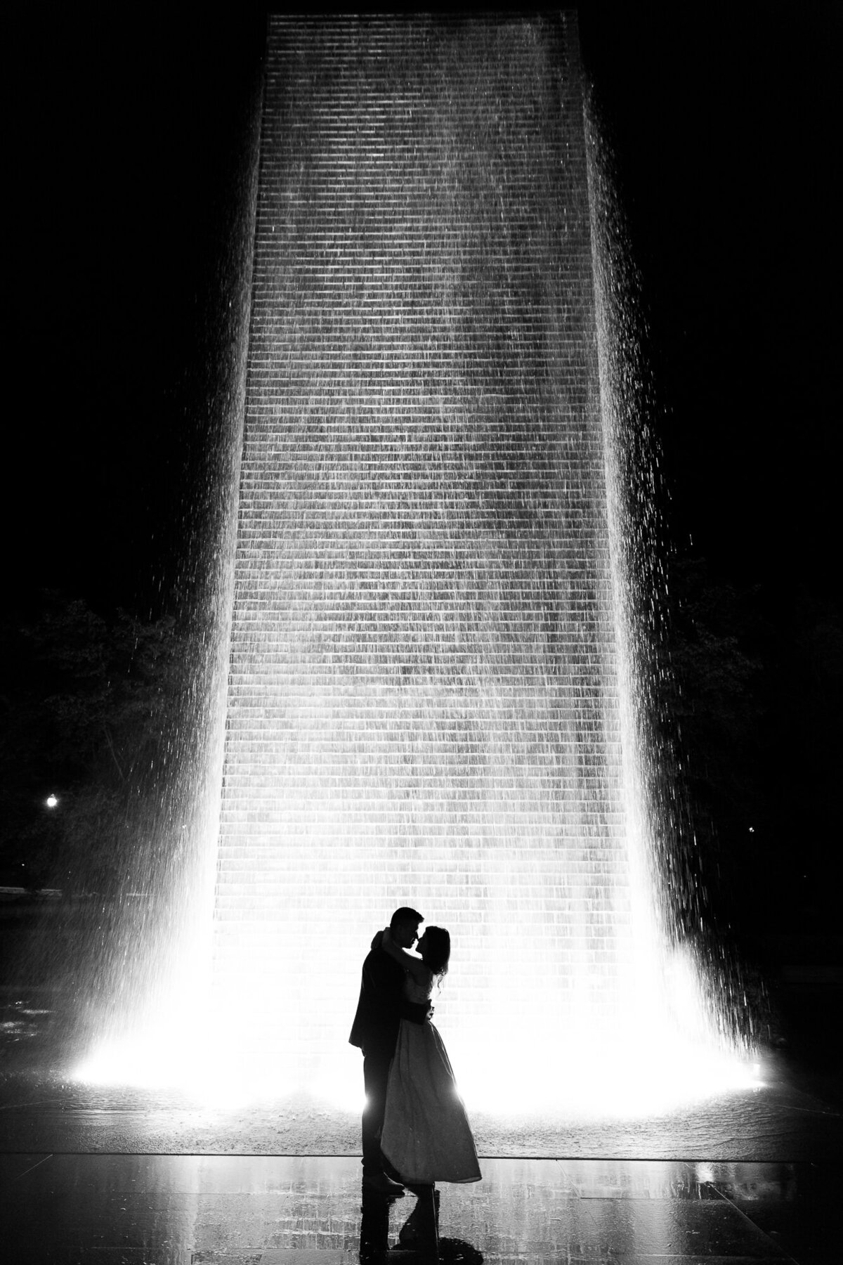 A wedding portrait at night of a couple kiss in front of the Millennium Park fountain.