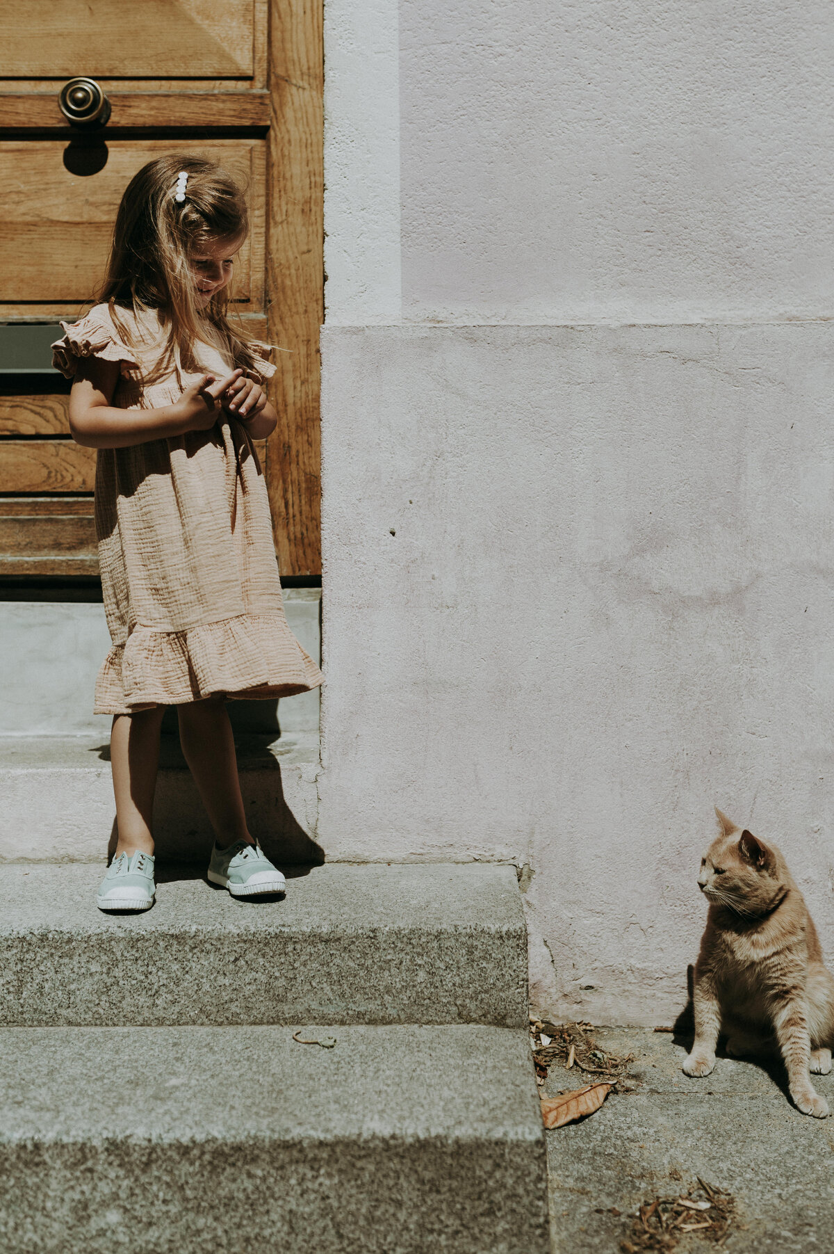 Meisje kijkt naar een kat op de stoep