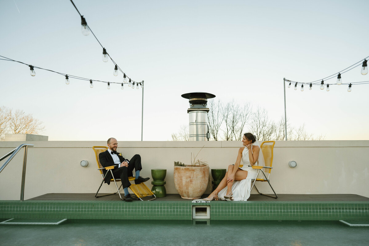 Newlyweds sit poolside on the roof of common house 