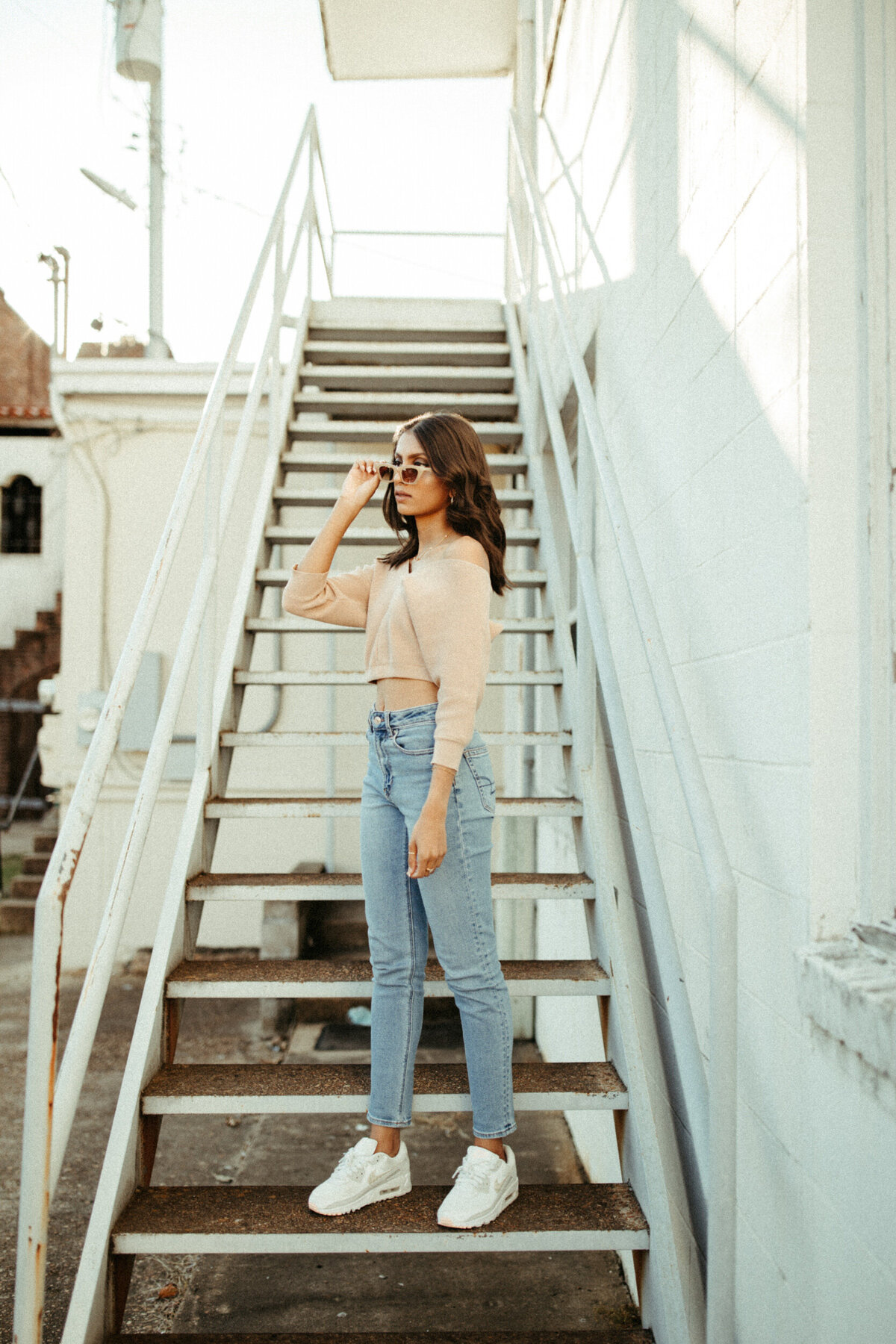 High school senior girl with vintage style wearing sunglasses and standing on a staircase downtown