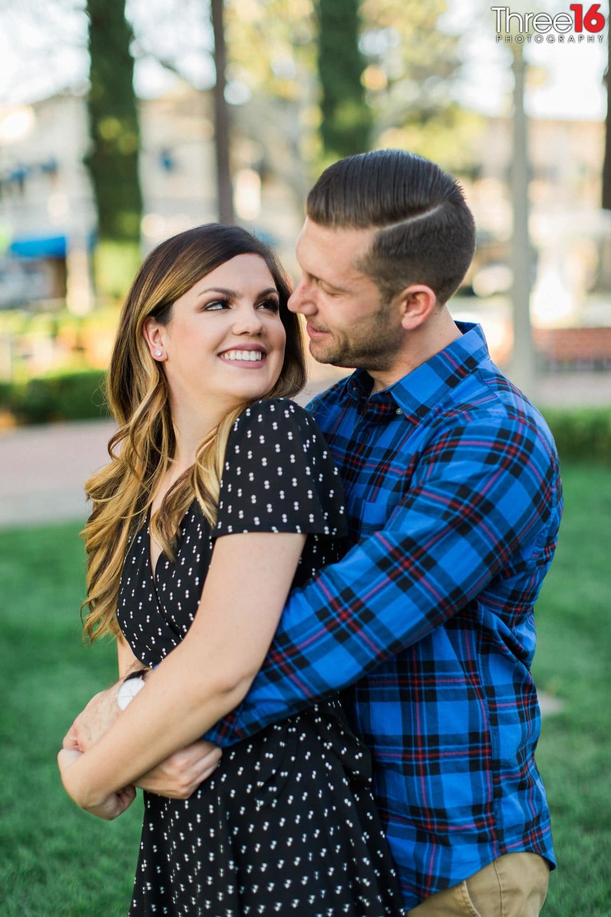 Bride to be looks back at her fiance with a smile as he embraces her