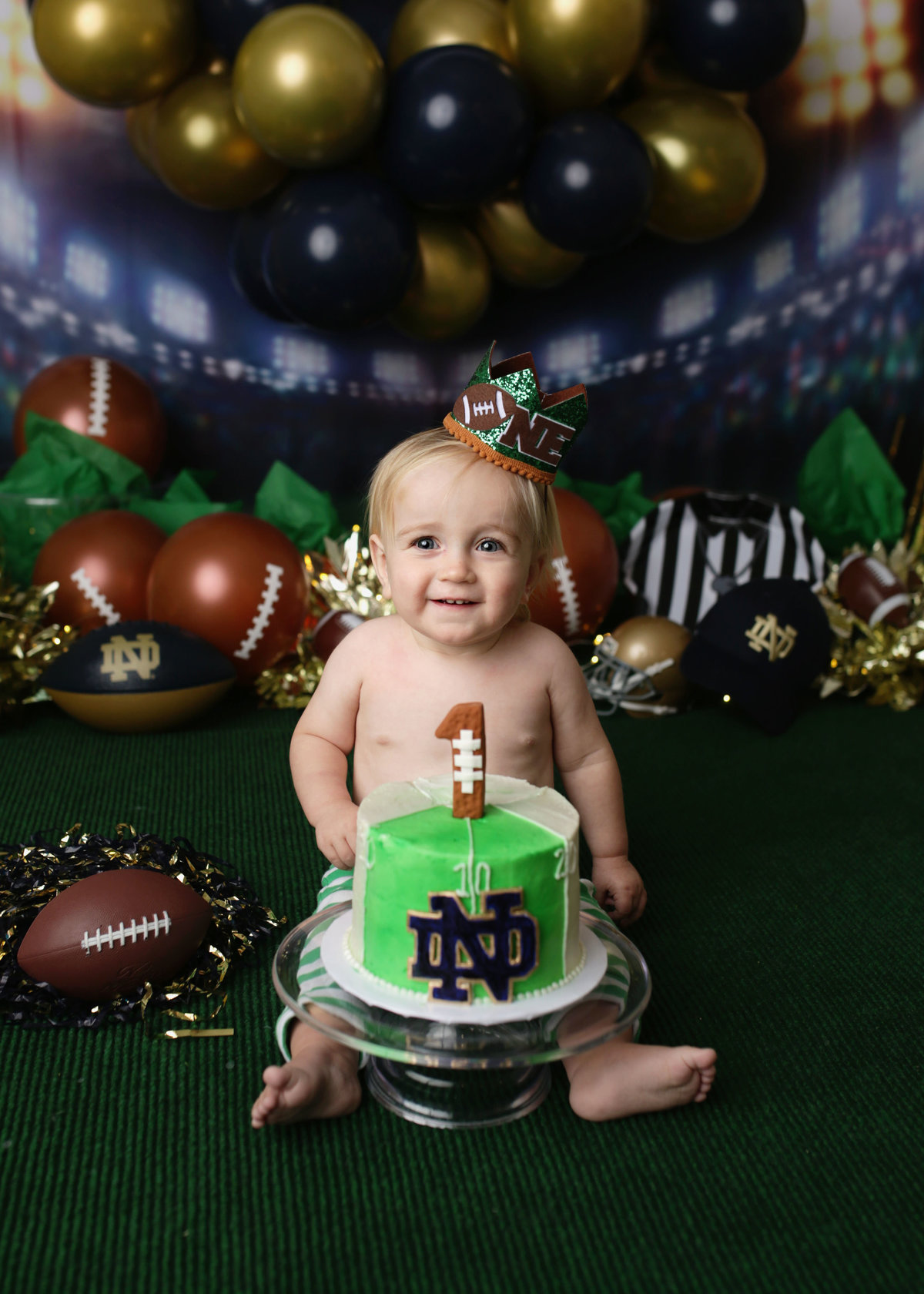 Baby boy celebrating first birthday with football themed cake and setup