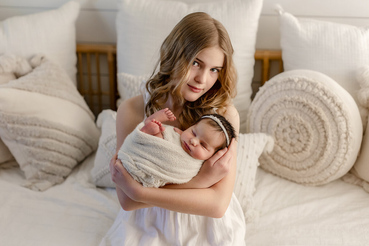 big sister holding baby sister in our denver studio for their newborn photos