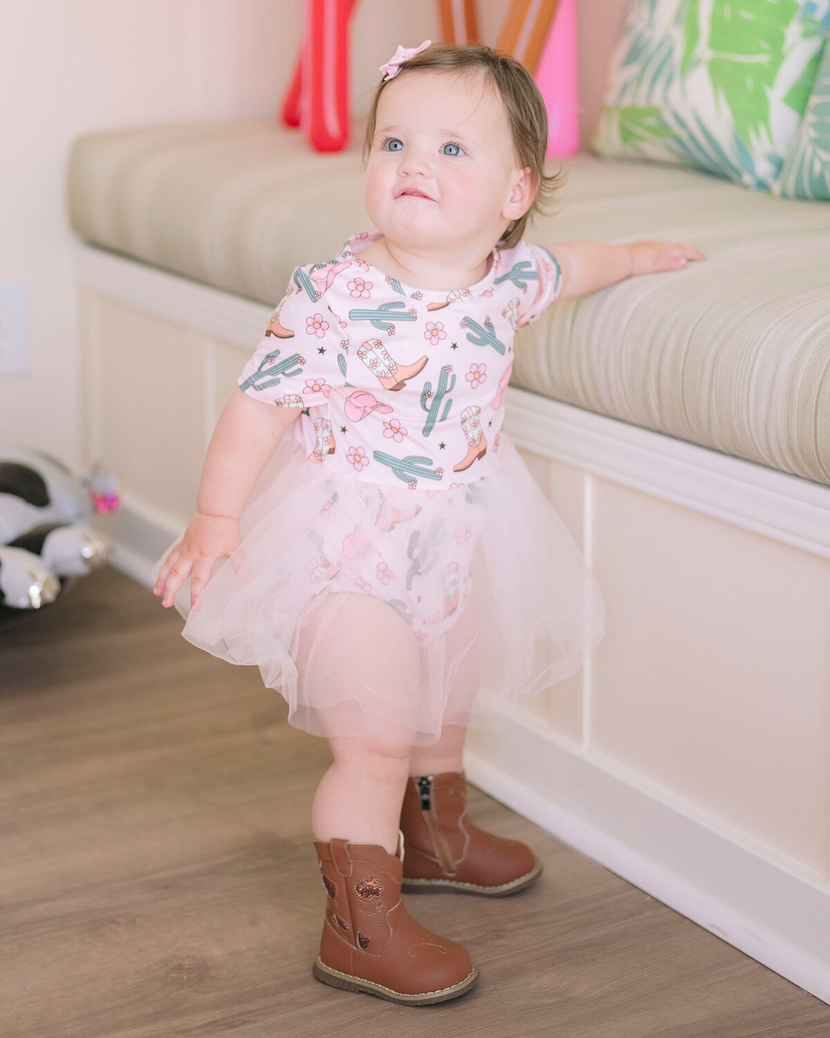 Portrait of baby girl wearing cowgirl boots and a tutu at her first birthday party in the San Francisco Bay Area, captured by a first birthday party photographer.