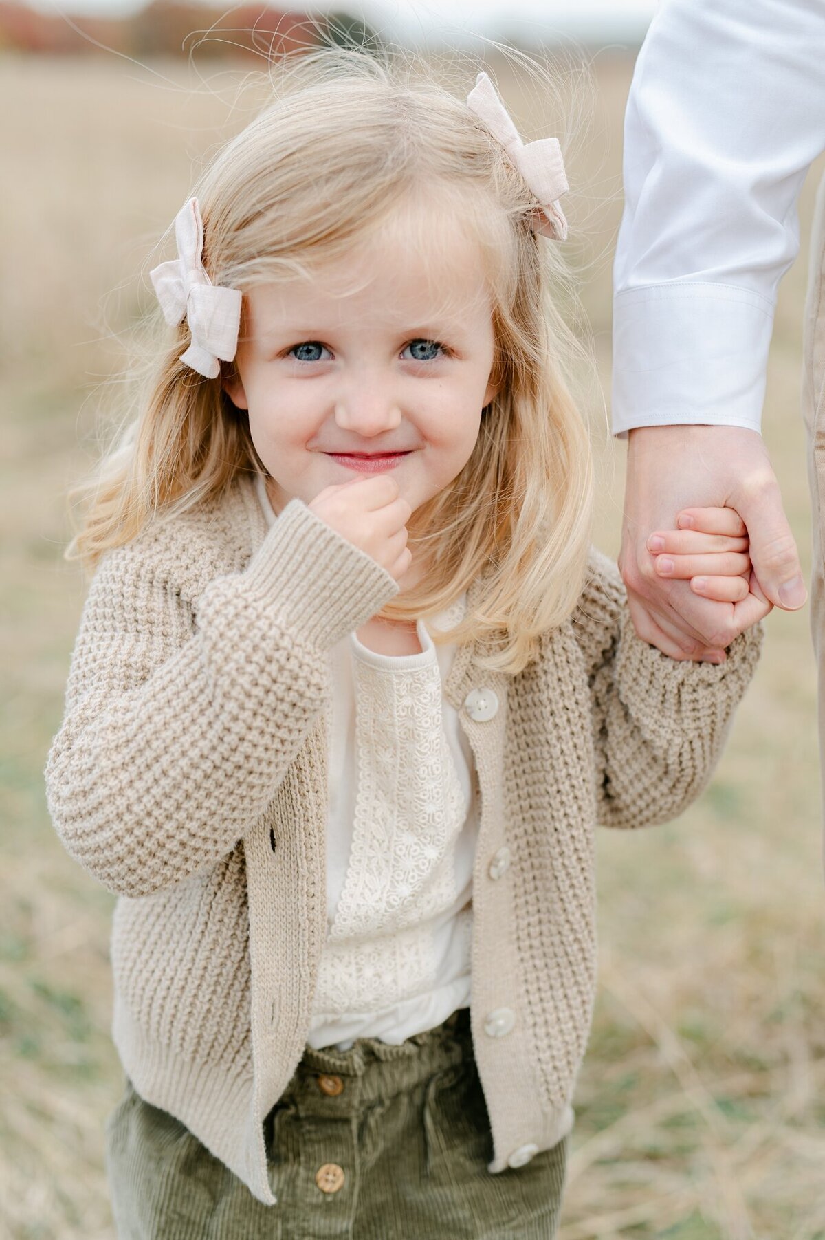 Little girl with a mischievous look on her face, holding her dad's hand