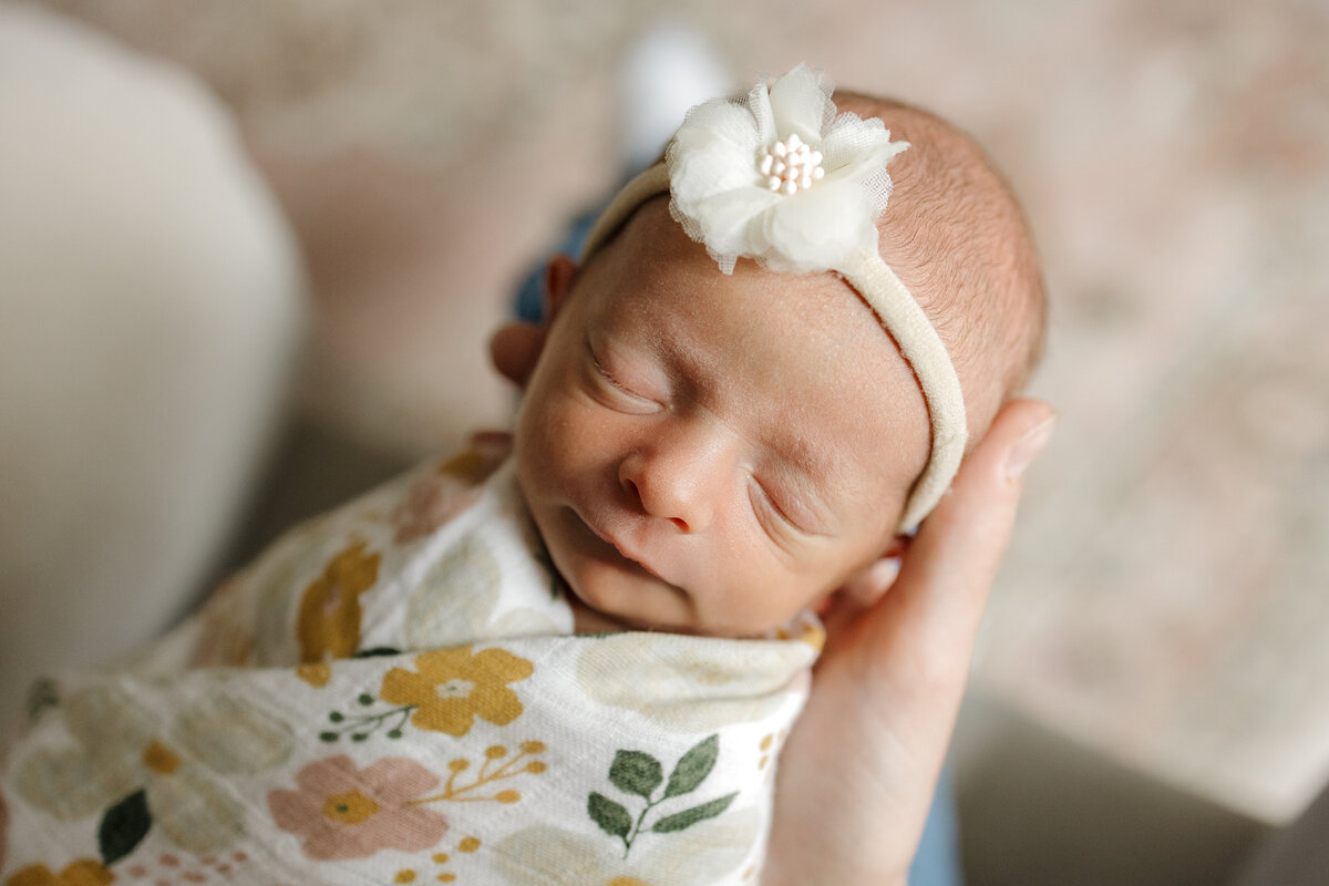 Longmont CO newborn sleeping with a soft smile while mom is holding her while rocking
