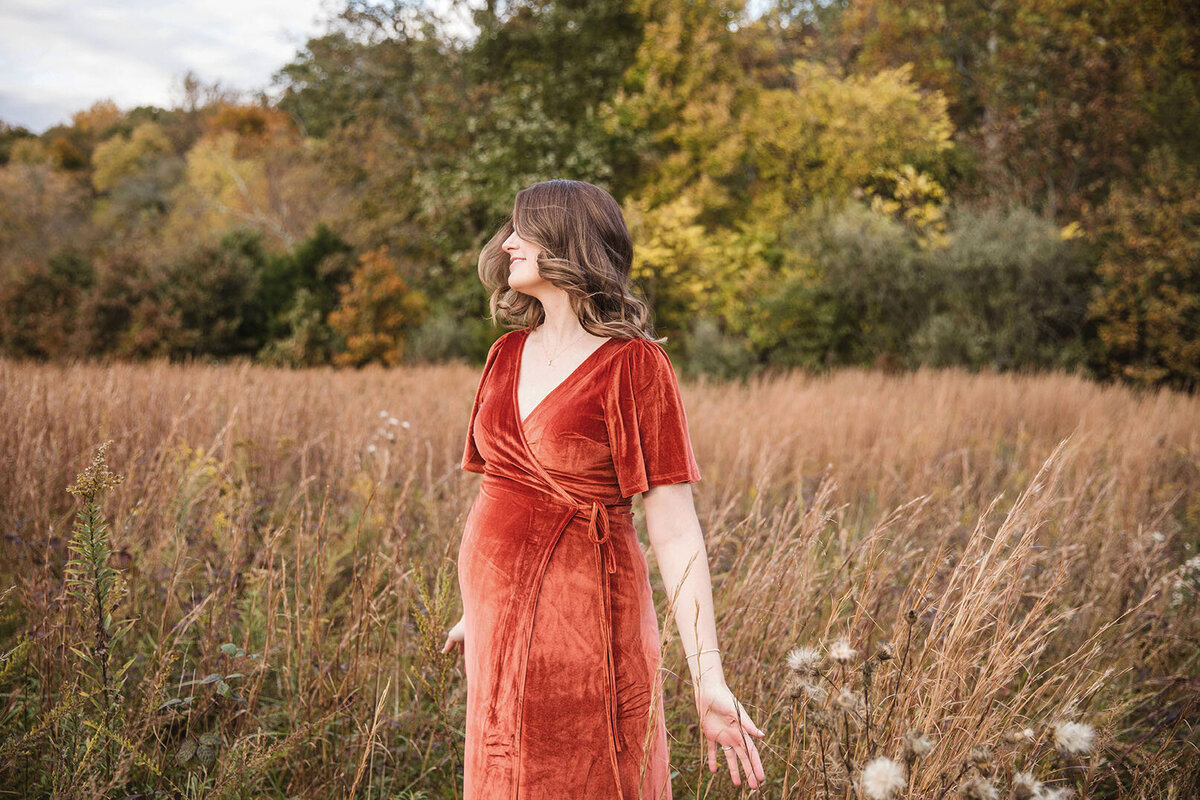 Pregnant woman in rust velvet dress in a field