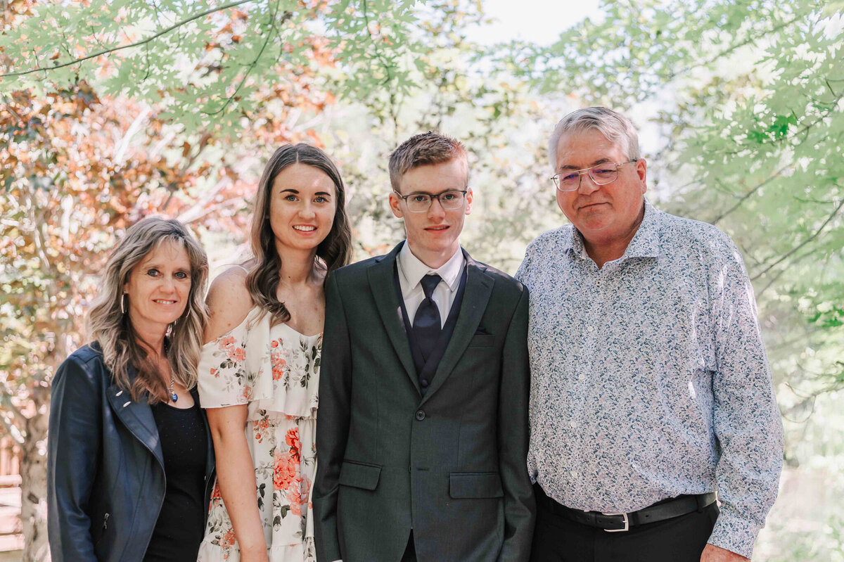Standing with the family on a path in front of trees. 