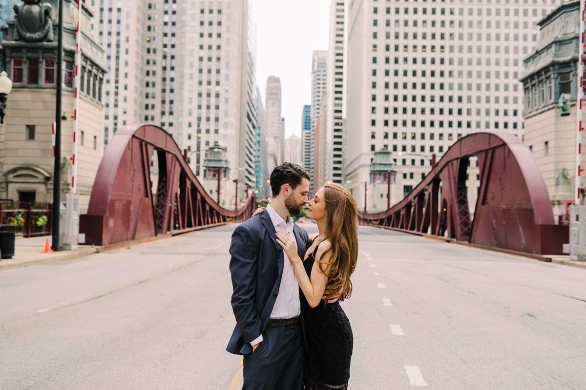 Engagement photo of couple standing in the middle of the LaSalle Street Bridge in downtown Chicago