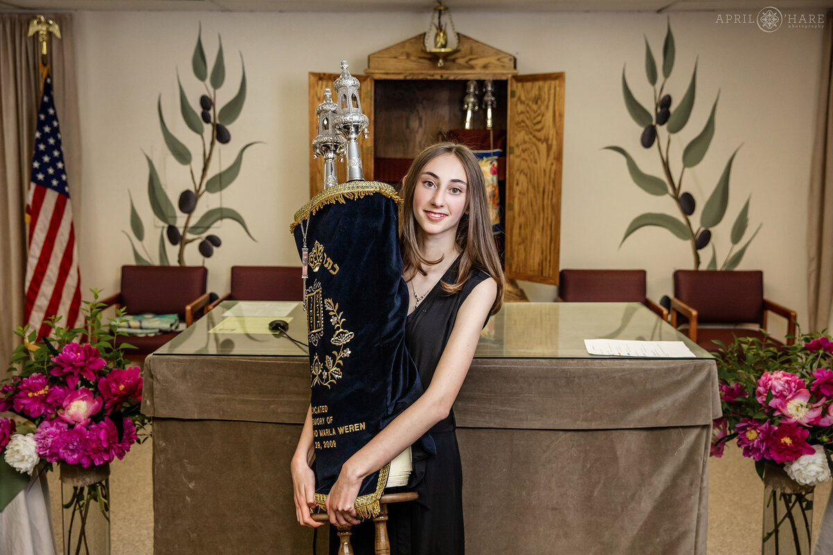 Young woman is photographed holding the Torah at her Bat Mitzvah in Colorado