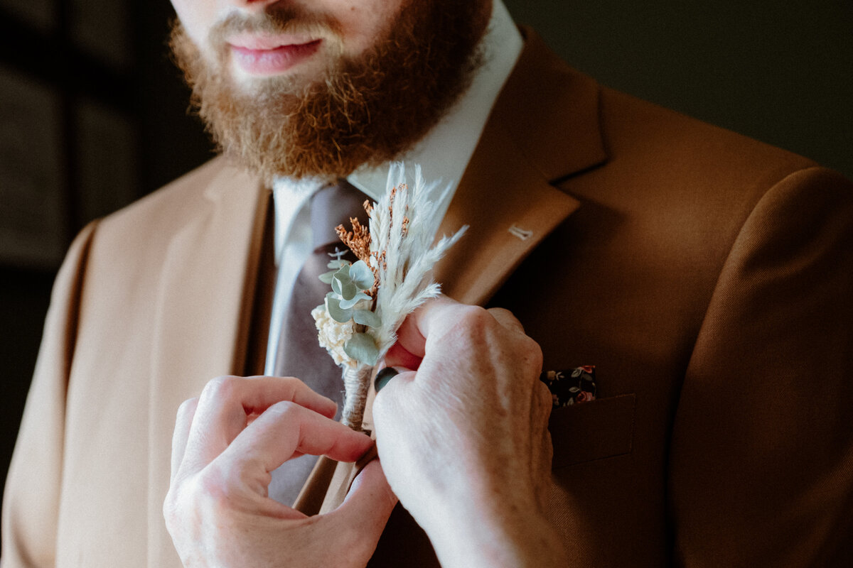 mother-of-the-groom-putting-on-the-boutonniere-on-the-groom-1