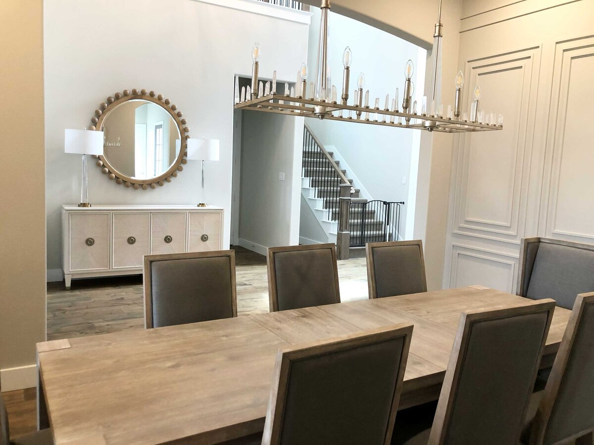Top-rated home design contractor showcasing the first house floor, decorated with a stylish dining table, elegant mirrors, and ceiling lamps that enhance the space's modern charm.
