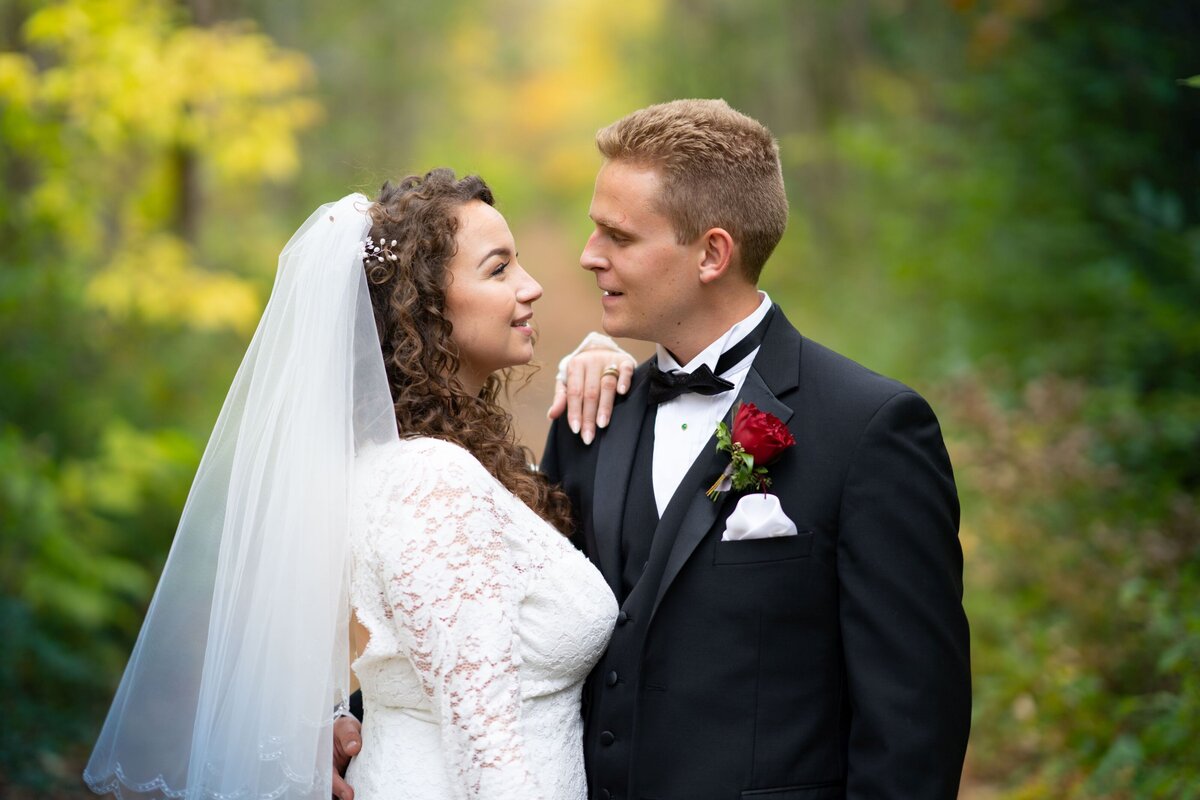 The bride and groom share a tender moment, gazing into each other's eyes with affection and love. The close-up captures their emotional connection and the joy of their wedding day, emphasizing their deep bond and the special nature of their union.