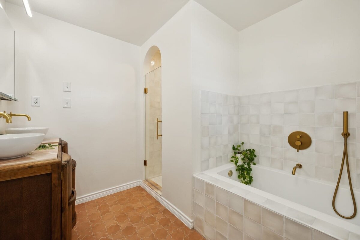Stylish primary bathroom at 3120 Chapel Downs Dr Dallas TX featuring soaking tub with brass fixtures, walk-in shower, and custom tile — Haven Realty Group.
