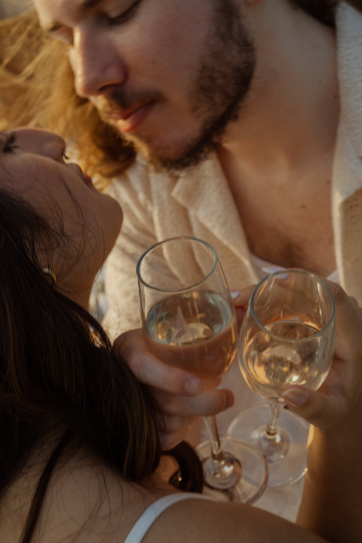 An intimate moment of a couple sharing a toast during a sunny engagement session near White Rock Lake in Dallas