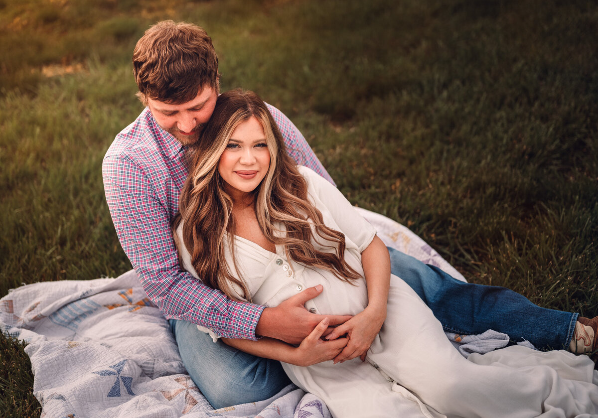 pregnant woman and husband laying in the grass