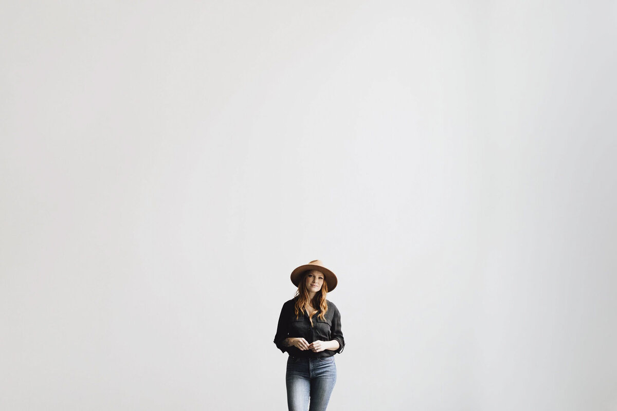 photographer along white wall with brown hat