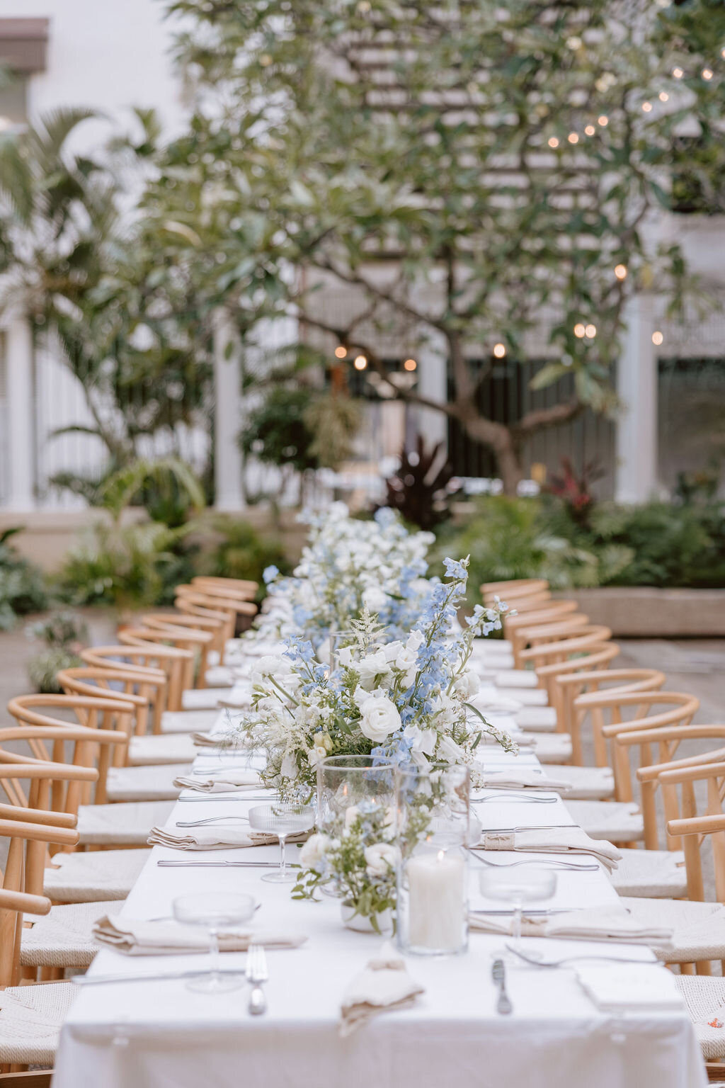 Wishbone chairs and long rectangle reception table with blue and white flowers on top