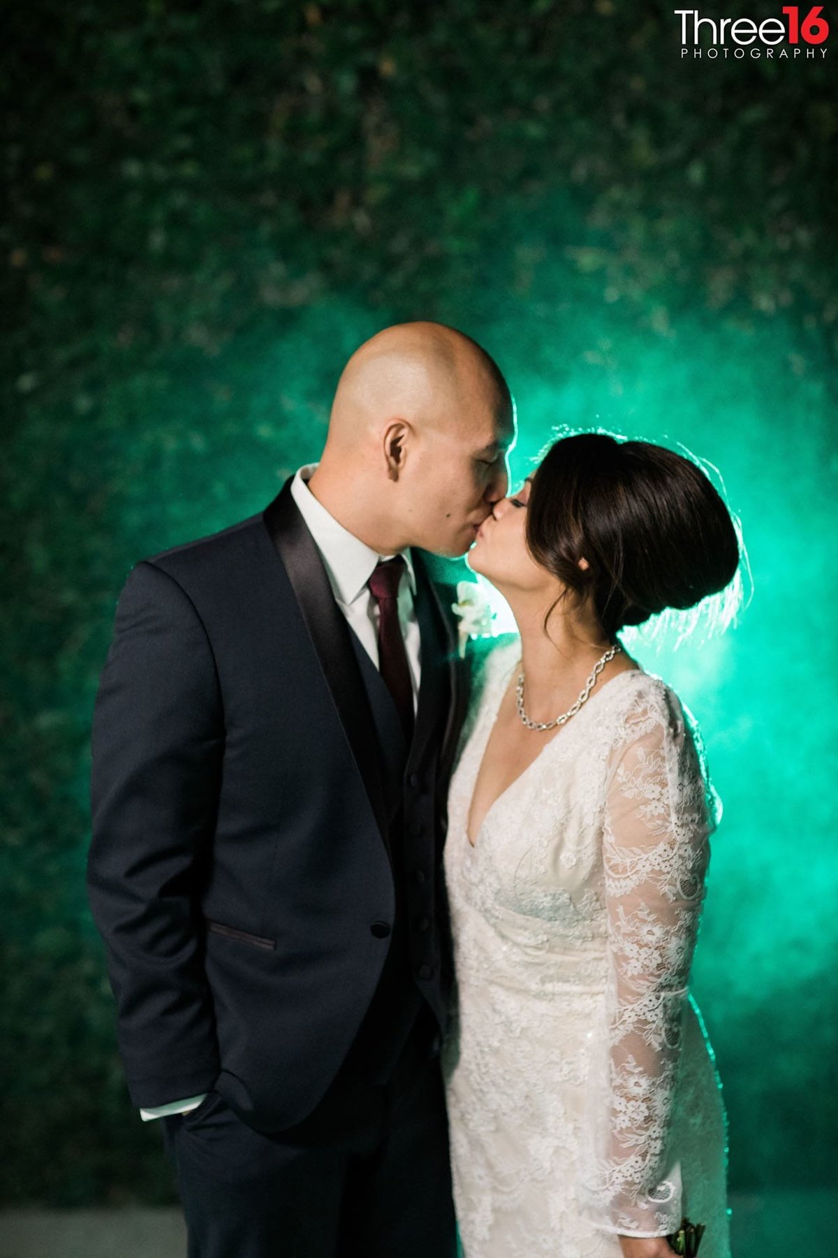 Bride and Groom share a sweet kiss at night with a greenish mist appears behind them