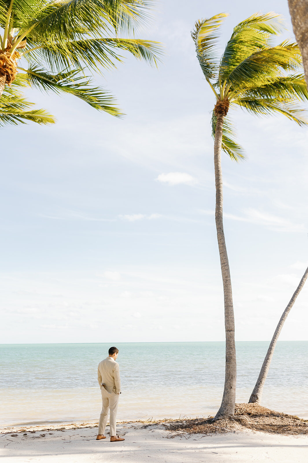 Austyn, dressed in a beige suit, waits on the sandy shores of Islamorada for the first look at his Florida Keys wedding.