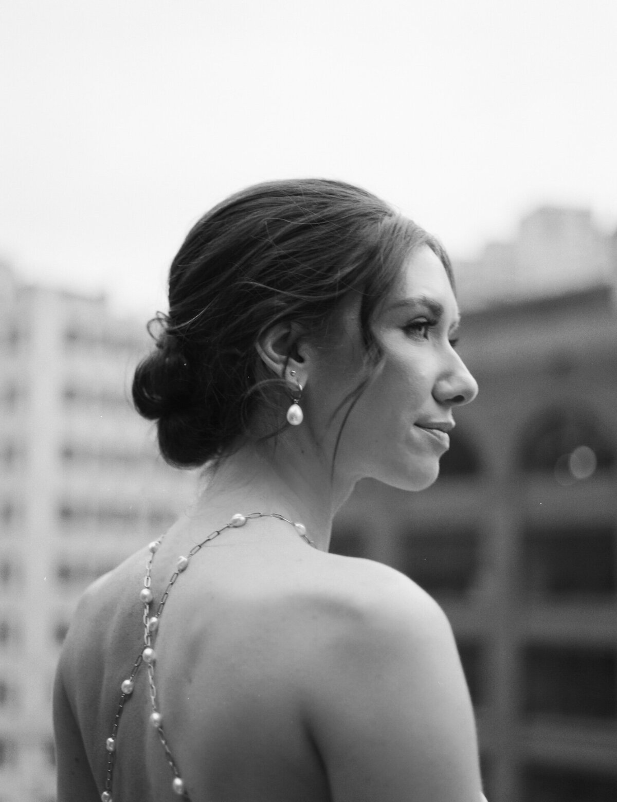 bride in backless pearl wedding dress, pearl earrings in rain on wedding day in Detroit, Shinola Hotel