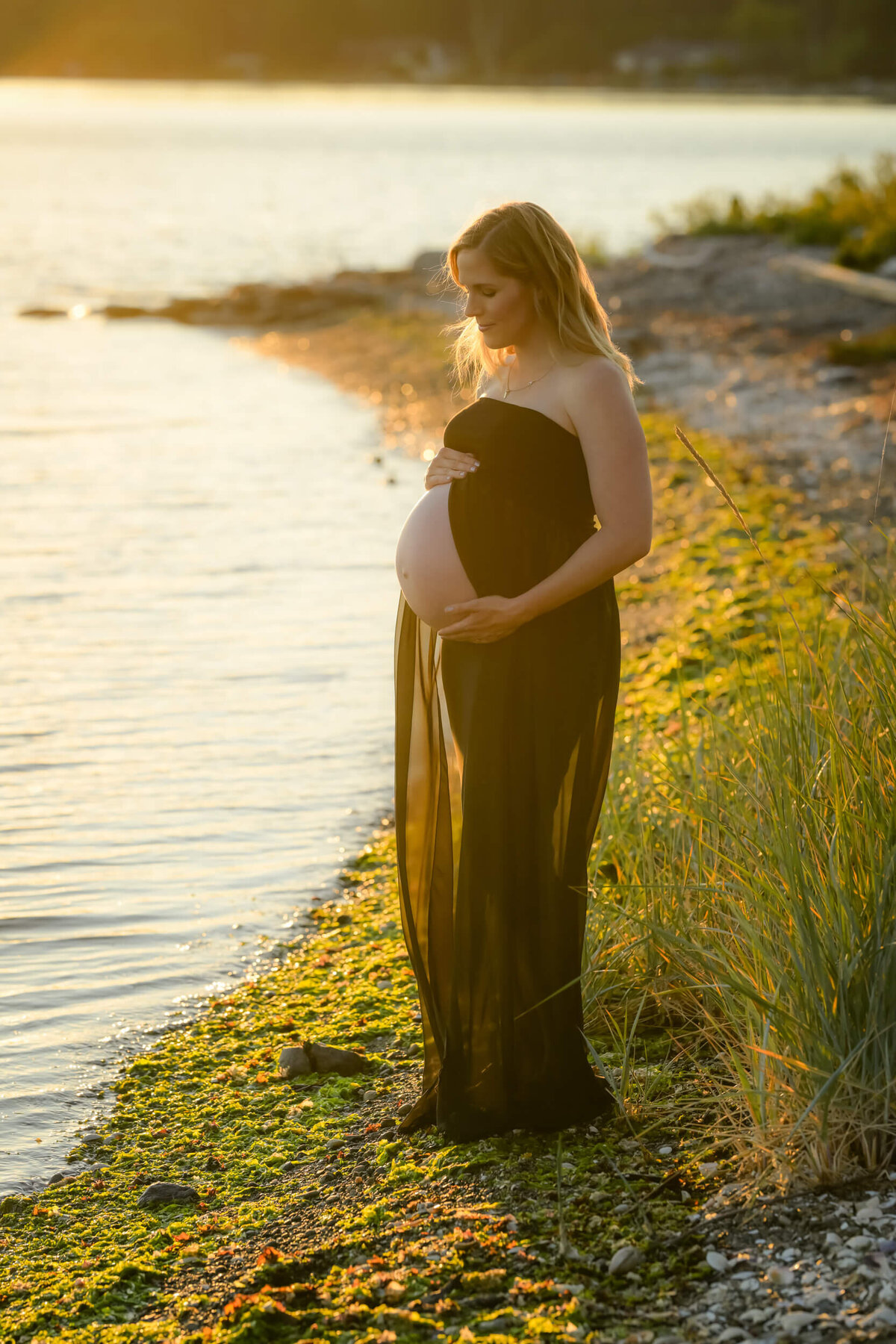 E. Benecki Photography captures this mom-to-be in a sheer black dress, beautifully illuminated by the warm sunset glow.