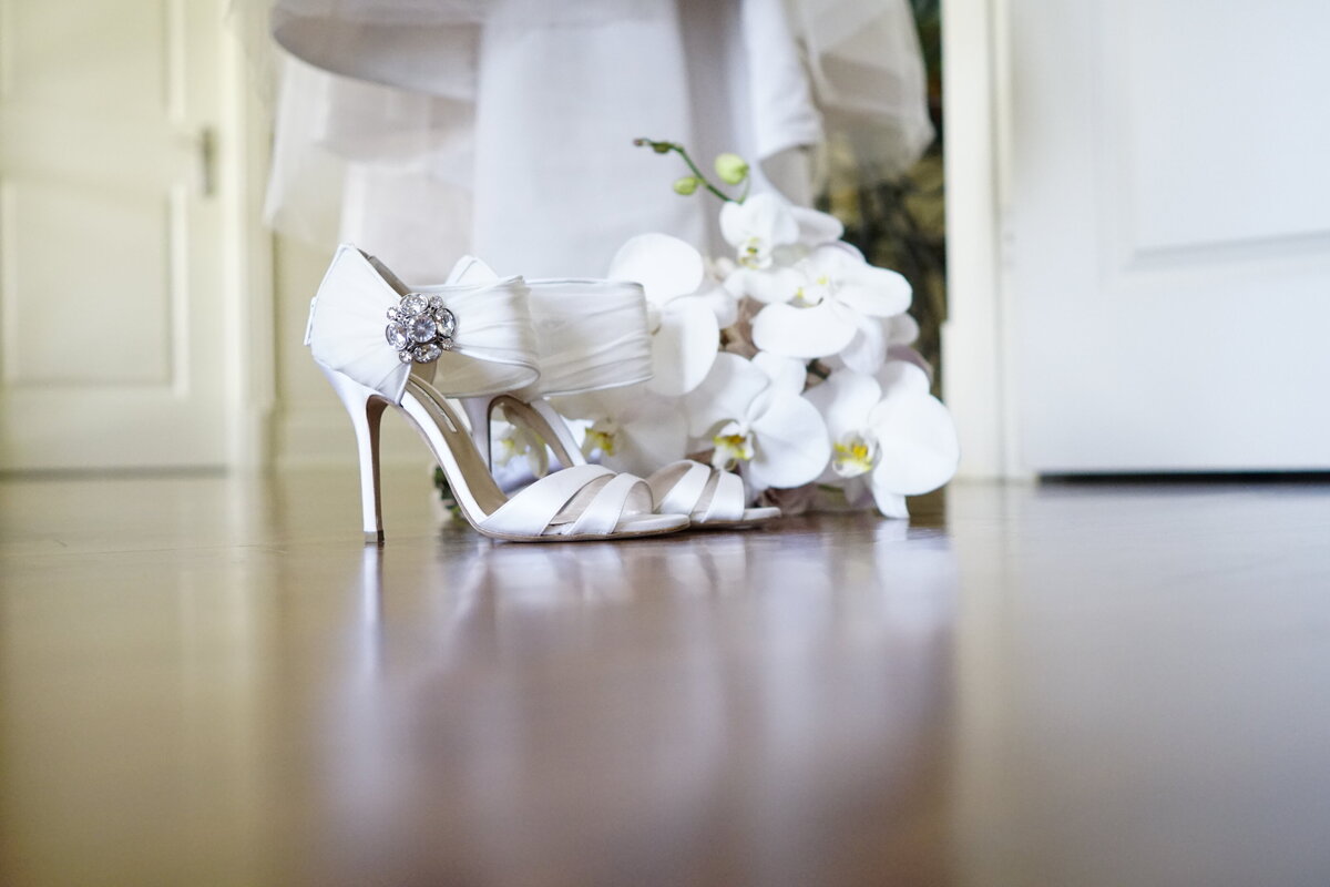 A close-up shot featuring the bride's elegant shoes alongside her bouquet, capturing the details of her bridal accessories. This image highlights the stylish elements and intricate details of the bride’s ensemble, adding a refined touch to the bridal portrait gallery.