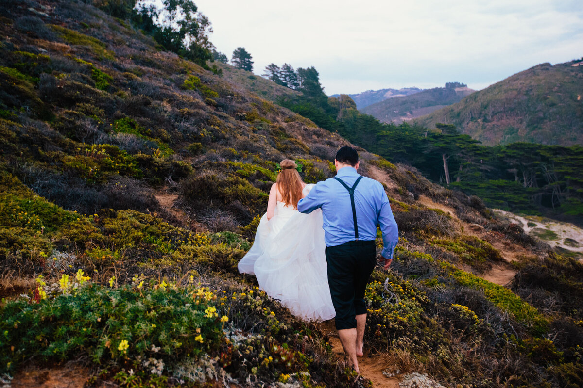 Bride and Groom walk up hillside in Big Sur during their adventure elopement in California Bay area