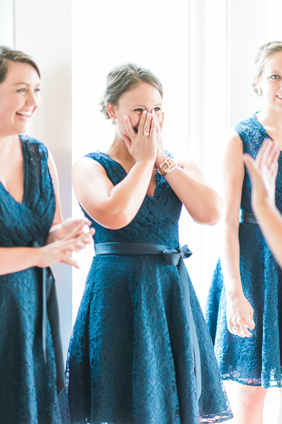 Bridesmaid holding back tears of joy as she looks at the bride for the first time.
