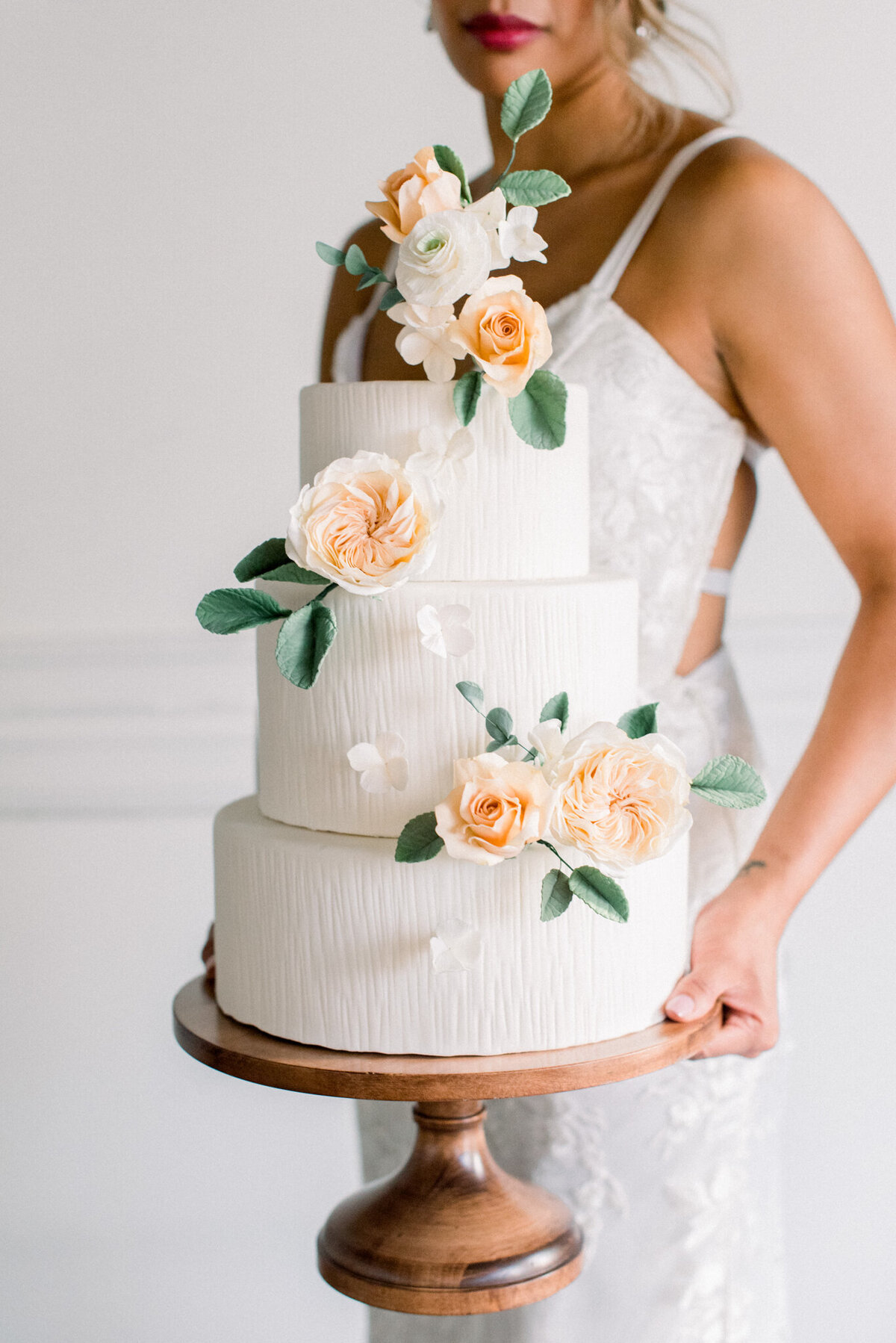 Romantic and elegant three-tiered white textured wedding cake, decorated with hand-crafted peach sugar roses, created by Brianne Gabrielle Cakes,  elegant cakes & desserts in Edmonton, AB, featured on the Brontë Bride Vendor Guide.