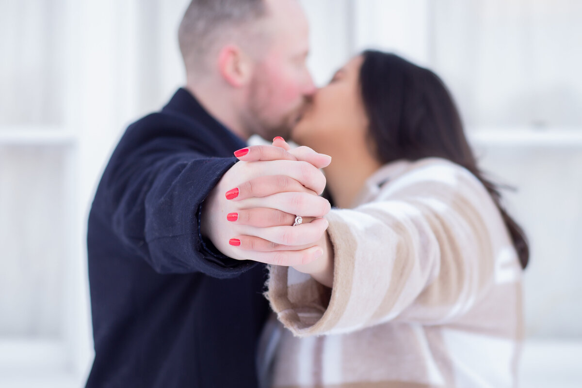 Engaged couple holding hands kissing