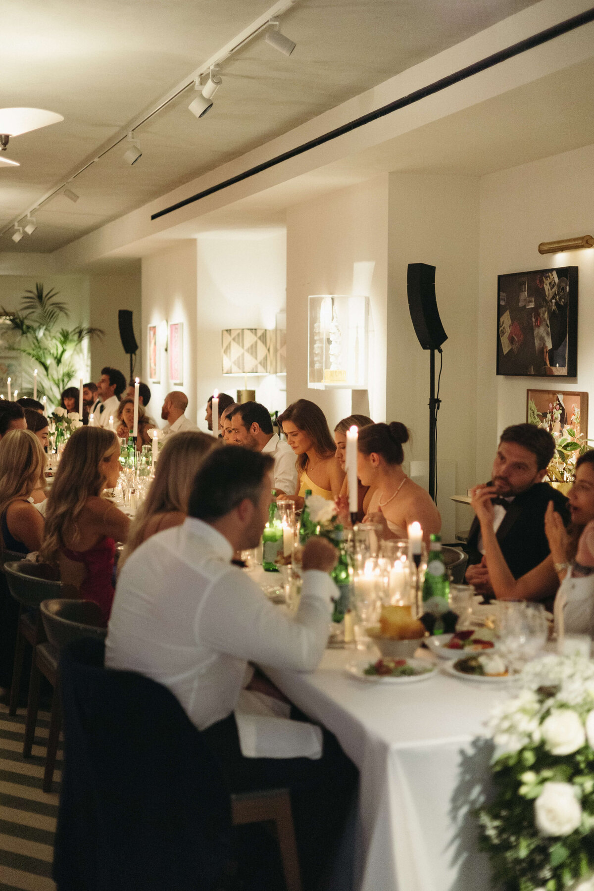 Candlelit dinner scene with guests seated at long reception tables

